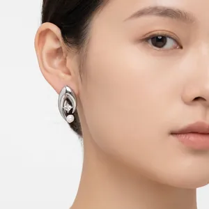 Détail de la boucle d'oreille œil en acier avec perle et zircone sur l'oreille du modèle