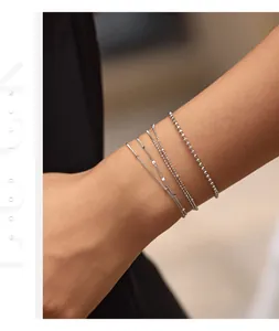 Exquisite detail shot of stacking S925 silver thin chain bracelets on a woman's wrist