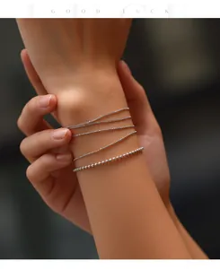 Detail view of minimalist S925 silver ultra-fine chain bracelets stacked on a wrist