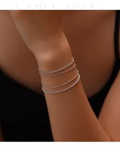 Close-up of minimalist S925 sterling silver thin layered chain bracelets on woman's wrist
