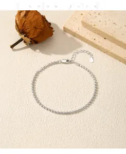 Detailed view of S925 silver minimalist fine bead bracelet on textured background