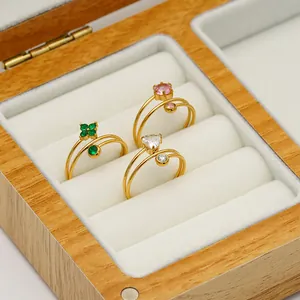 Detalle de anillos de doble hilo chapados en oro de 18K con circonitas en caja de madera