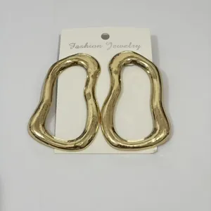 Detail shot of gold-toned irregular oval hoop earrings displayed on white jewelry card.