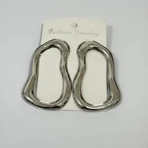 Detailed close-up of oversized irregular silver hoop earrings on a white fashion jewelry card