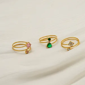 Vista detallada de anillos de acero inoxidable bañados en oro de 18K con circonitas de colores.