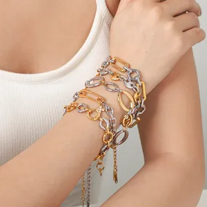 Close-up of mixed gold and silver stainless steel geometric stackable bracelets on wrist