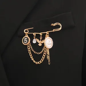 Detail einer goldenen Brosche mit Quastenketten, '5' und 'Je T'aime' Anhängern