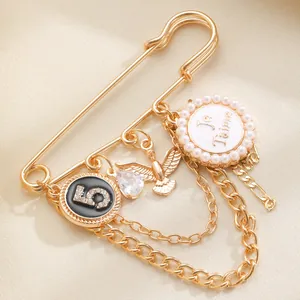 Detailansicht der eleganten goldfarbenen Quastenkette Brosche mit Je t'aime und Nummer 5