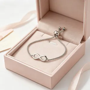 Close-up of a silver infinity symbol adjustable bracelet inside a premium pink jewelry box