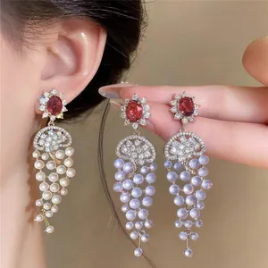 Detail showing 18k gold plated tassel earrings with sparkling red zircon and pearls