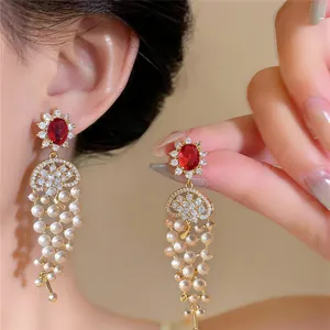 Detailed view of 18k gold plated earrings with red zircons and elegant pearl tassels