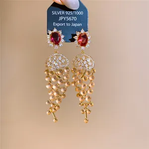 Close-up of luxury 18k gold plated zircon tassel earrings with red gemstone