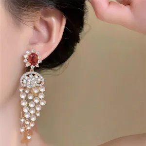 Detailed view of luxury 18k gold-plated tassel earrings featuring red zircon and white beads