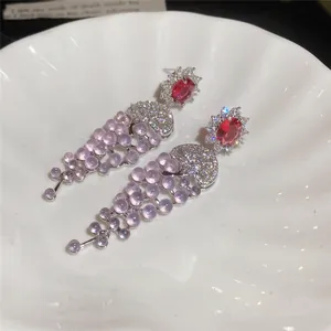 Close-up of 18k gold plated earrings with purple grape-like zircon tassels