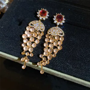 Detail shot of luxury 18k gold plated cubic zirconia tassel earrings featuring red stones.