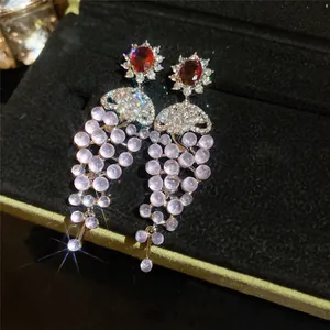 Detail view of 18k gold plated zircon tassel earrings with pink beads