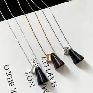 Gros plan de pendentifs en bois minimalistes et d'accents métalliques sur colliers.