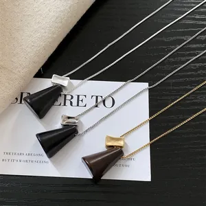 Long collier minimaliste de style coréen avec pendentif en bois et métal décoré.