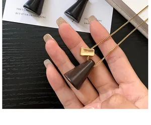 Gros plan détaillé d'un collier avec pendentif cône en bois et chaîne dorée élégante