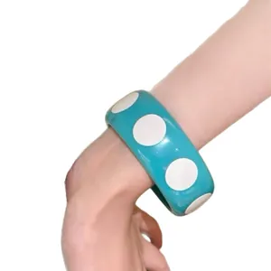 Stylish turquoise acrylic resin bangle bracelet with bold white polka dot pattern on arm
