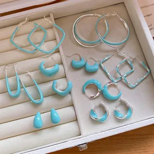 Collection de boucles d'oreilles géométriques en émail turquoise dans un écrin à bijoux blanc