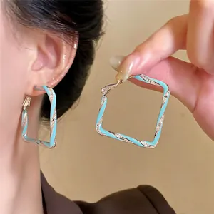 Vue détaillée de boucles d'oreilles créoles carrées torsadées en émail bleu clair