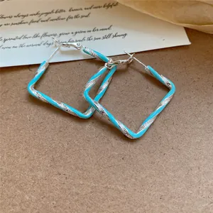Vue détaillée des créoles carrées torsadées en émail turquoise sur fond de papier vintage