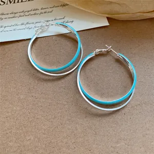 Gros plan de boucles d'oreilles créoles doubles en émail bleu clair et argent sur fond