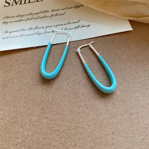 Gros plan de boucles d'oreilles en émail bleu clair en forme de U argentées