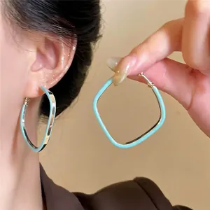 Détail de boucles d'oreilles losanges en émail bleu clair avec tiges en argent