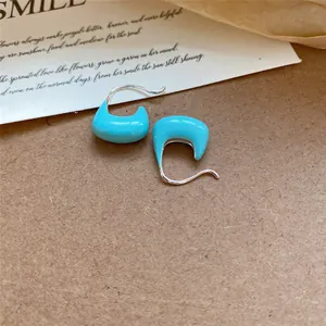 Gros plan de boucles d'oreilles créoles en émail turquoise avec tiges en argent.