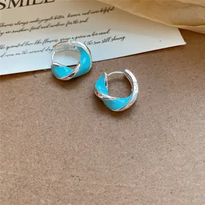 Gros plan détaillé de créoles en argent avec un design torsadé en émail bleu ciel
