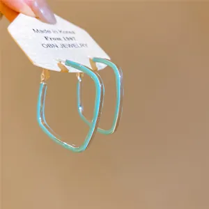 Détail de boucles d'oreilles créoles losanges en émail vert menthe sur carte de présentation