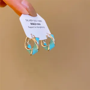 Gros plan détaillé de boucles d'oreilles créoles torsadées en argent et émail bleu