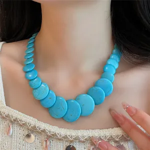 Primo piano di una collana di perle tonde turchesi indossata dal collo di un modello