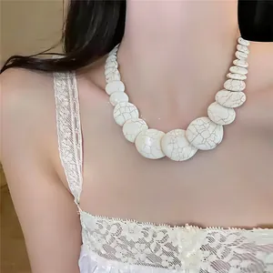 Dettaglio della collana di perle di marmo bianco indossata con un abito di pizzo