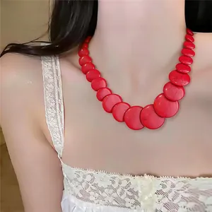 Dettaglio che mostra una vivace collana di perle rosse circolare su una modella