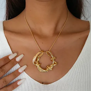 Vue détaillée d'un collier pendentif géométrique doré irrégulier torsadé sur une chaîne serpent