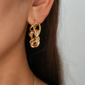 Gros plan d'une boucle d'oreille créole en chaîne torsadée dorée portée par un mannequin