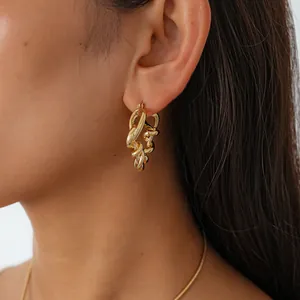 Gros plan élégant d'une boucle d'oreille dorée à nœud torsadé irrégulier sur un modèle