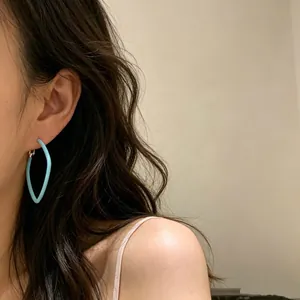 Primo piano di una modella con orecchini a cerchio geometrici azzurri in smalto opaco