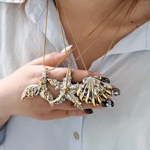 Detailed view of three metallic ocean-themed pendants: a starfish, shell, and fishtail.