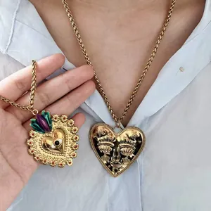 Detail view of heart-shaped gold pendants with unique face and eye engravings on chains