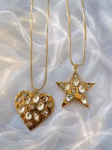 Close-up of gold heart and star necklaces with sparkling crystal inlays on soft fabric