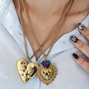 Detail showing two ornate gold heart necklaces with eye designs on a model's neck
