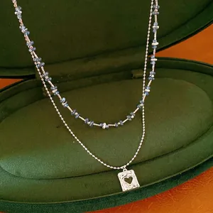 Dubbellaagse zilveren ketting met blauwe stenen kralen en een vierkante harthanger.