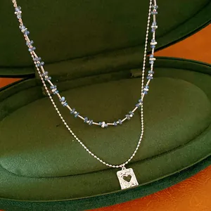 Gedetailleerd beeld van een dubbellaagse ketting met blauwe kralen en hart hanger.