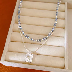 Detailopname van de dubbellaagse ketting met blauwe kralen en hartvormige hanger