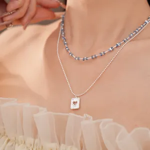Gedetailleerd zicht op een dubbellaagse ketting met blauwe kralen en hart hanger