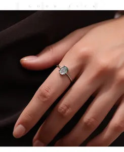 Close-up of a minimalist S925 sterling silver ring with oval synthetic moss agate stone